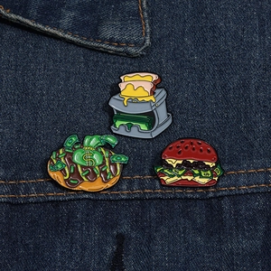 Detailed view of three fun enamel pins depicting money burger and toast on denim jacket