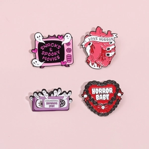 Set of 4 gothic horror enamel pins featuring a TV, heart organ, VHS tape, and cake