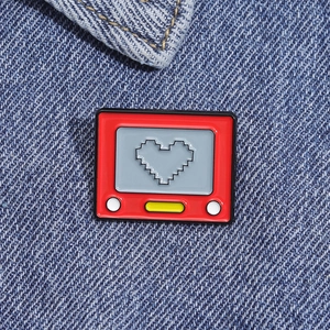 Vintage red television enamel pin with pixel heart pattern on blue denim background