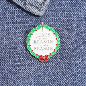 Macro shot of Christmas wreath enamel pin with religious text on denim fabric