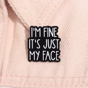 Gros plan d'un pin's en émail noir avec slogan humoristique sur tissu rose
