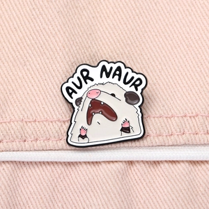 Detailed close-up of a funny enamel opossum brooch with AUR NAUR text on pink fabric