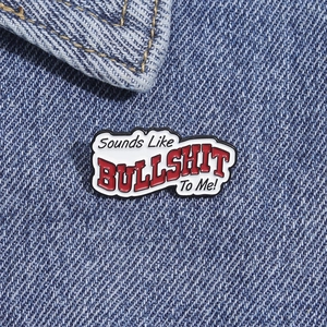 Macro shot of red and white enamel badge on denim with text Sounds Like BULLSHIT To Me!