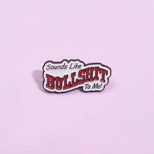 Cartoon metal enamel pin badge featuring red BULLSHIT text on a white background