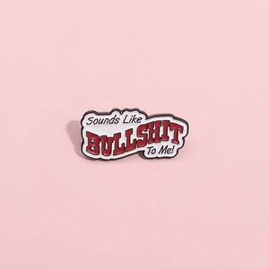 Red and black enamel pin with Sounds Like BULLSHIT To Me text on pink background