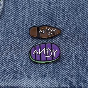 Detailed macro view of metal enamel ANDY sole pins on blue denim fabric background