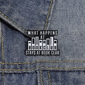 Détail du pin's en émail Book Club avec texte noir et blanc sur veste en jean