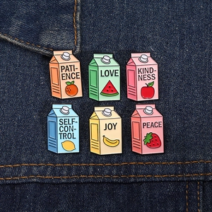 Dettaglio di sei spille smaltate a forma di cartoni di latte alla frutta su jeans