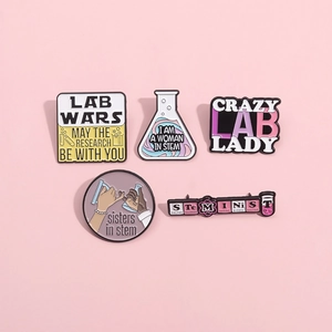 Close-up of five colorful STEM themed enamel pins featuring lab beakers and slogans