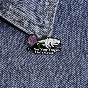 Détail d'une épingle émaillée main de squelette avec rose violette sur veste