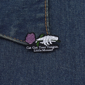 Détail d'une épingle émaillée main de squelette gothique tenant une rose sur denim