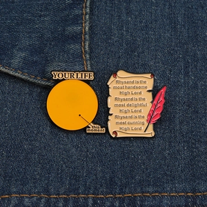 Détail du lot de broches en émail jaune avec citations et plume sur fond denim