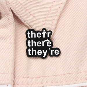 Detail of grammar enamel pin with their there they are text on a pink denim jacket