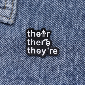 Macro detail of English grammar enamel pin with their there they're text on denim