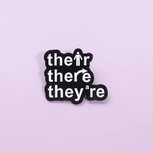 Creative enamel pin badge featuring their there they're word design on purple background