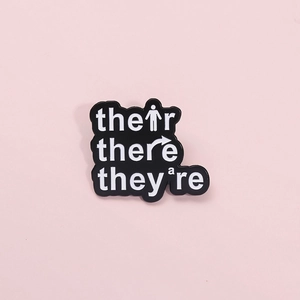 Funny English grammar enamel pin featuring Their There They're text on a black badge