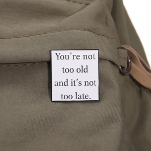 Broche en émail blanc avec citation inspirante sur un sac en toile verte