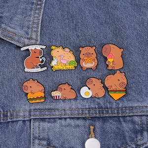 Set mit acht bunten Capybara Emaille Pins auf blauem Denim Hintergrund präsentiert