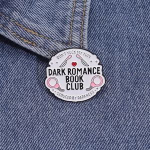 Detail der Dark Romance Book Club Emaille-Anstecknadel mit Handschellen auf Denim-Jacke