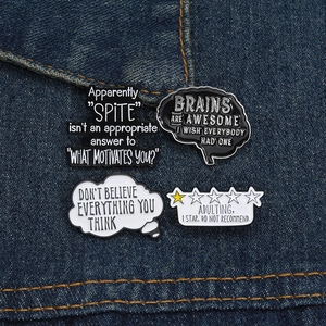 Detail of four creative black and white enamel brain pins pinned on blue denim fabric