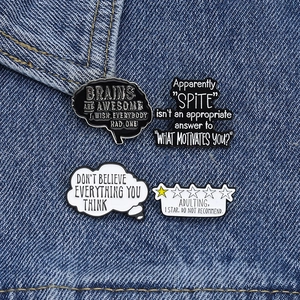 Close-up of funny minimalist black and white brain enamel pins on denim jacket