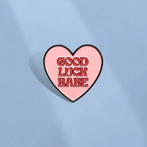 Herzförmige Emaille-Brosche in Rosa mit Good Luck Babe Schriftzug und Metalleinfassung