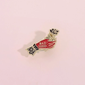 Broche émaillée gothique main tenant une rose noire avec lettrage Bad Seed sur rose