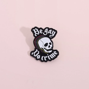 Épingle en émail crâne arc-en-ciel avec lettrage Be Gay Do Crime sur fond rose