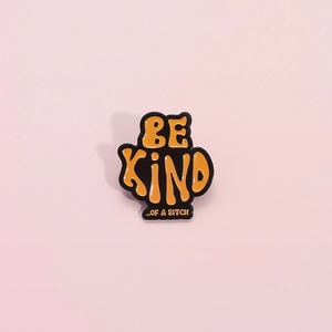 Orange enamel pin with 'BE KIND ..OF A BITCH' funny slogan in trendy wave shape design
