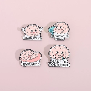 Ensemble de quatre pin's en émail rose en forme de cerveau aux motifs de dessins animés