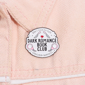 Detail der Dark Romance Book Club Emaille-Anstecknadel mit rosa Handschellen auf Denim