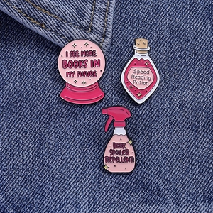 Detailed view of three pink enamel lapel pins with reading book themes on denim background