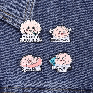 Détail de quatre épingles créatives en émail rose en forme de cerveau sur tissu denim