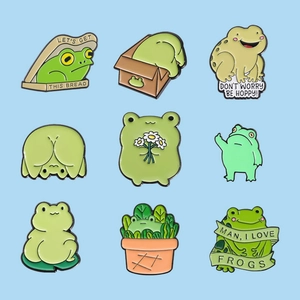 Set of nine cute cartoon frog enamel pins in various poses on a blue background