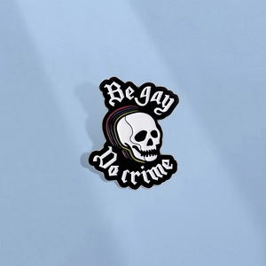 Pin's tête de mort arc-en-ciel avec texte Be Gay Do Crime sur fond bleu clair