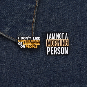 Funny enamel pins with humor quotes pinned on a blue denim fabric jacket background