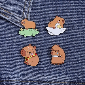 Detail showing four cute enamel capybara badges pinned on dark blue denim fabric background