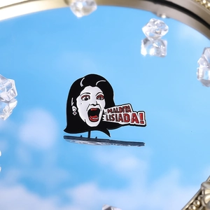 Mirror reflection shot of Maldita Lisiada enamel pin against blue sky with crystals