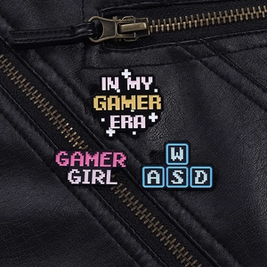 Detail shot of three pixel art gamer pins pinned on a black leather jacket texture