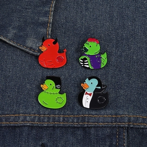 Close-up of four Halloween horror themed enamel duck pins on denim fabric background