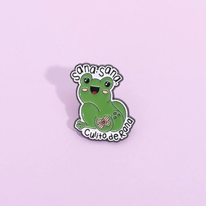 Funny green cartoon frog enamel pin badge with heart bandage on a purple background