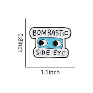 Dettaglio macro della spilla smaltata con testo Bombastic Side Eye e misure di taglia