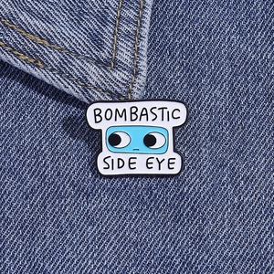 Dettaglio della spilla smaltata Bombastic Side Eye con occhi blu su tessuto denim