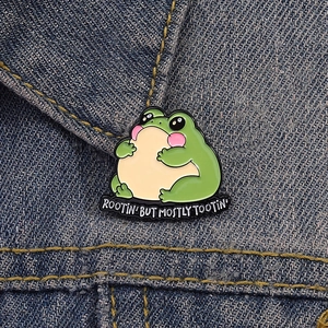 Funny green frog enamel pin with slogan on denim background for backpack decoration