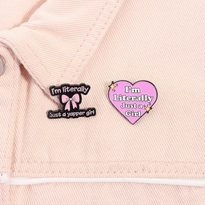 Detail of pink heart and bow enamel pins with catchy slogans on pink denim jacket