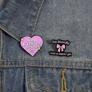 Pink heart and bow enamel badges with funny slogans pinned on a denim jacket background