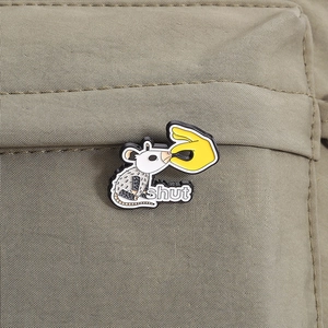 Gros plan d'un pin's émaillé d'oppossum sur un sac en toile kaki montrant les détails