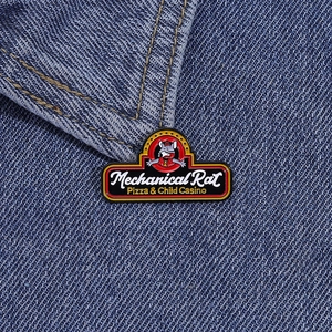 Close-up of Mechanical Rat enamel pin on a blue denim jacket collar with sharp details
