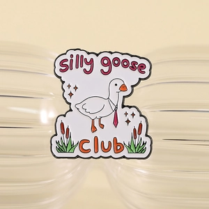 Detailed view of enamel silly goose club pin on a textured glass surface with star details