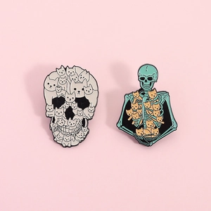 Cute enamel pins featuring white skull cats and mint green skeleton chest with kittens